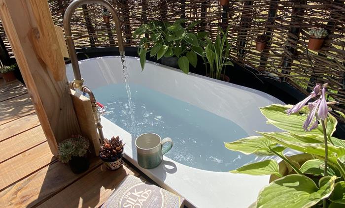 Outdoor bath at one end of deck area and verandah.